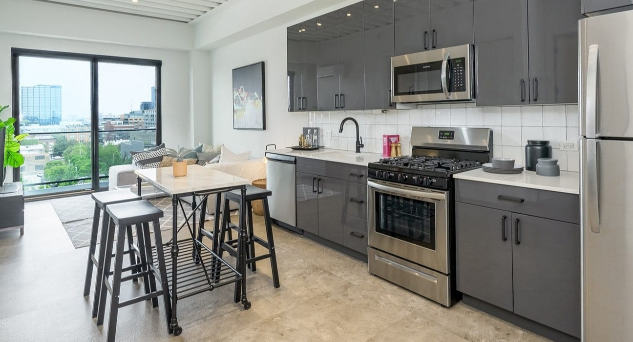Modern kitchen at The Jax in Chicago, featuring sleek gray cabinetry, stainless steel appliances, and a compact dining area