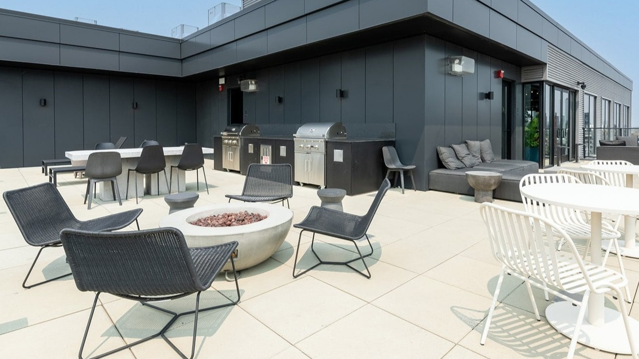 Versatile rooftop area at The Jax in Chicago, featuring outdoor dining tables, grilling stations, and a modern fire pit lounge