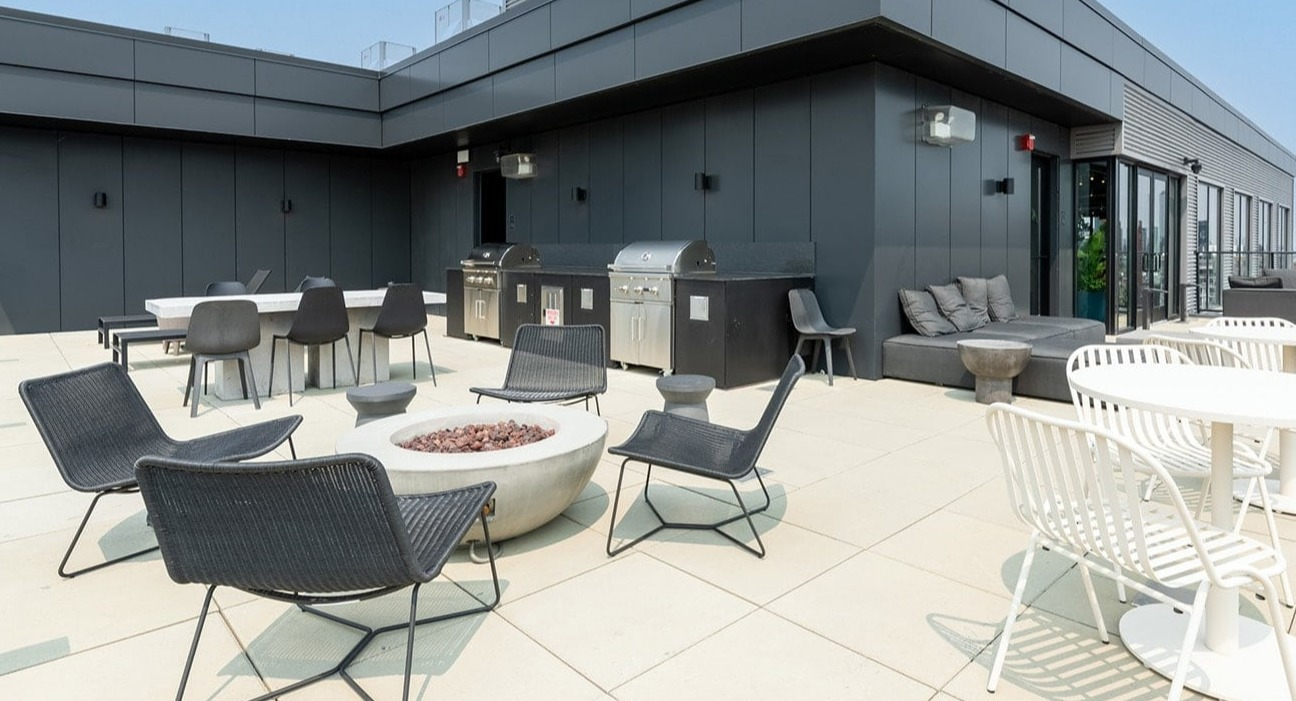 Versatile rooftop area at The Jax in Chicago, featuring outdoor dining tables, grilling stations, and a modern fire pit lounge