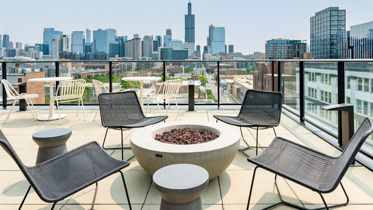 Stylish rooftop patio at The Jax in Chicago, featuring a modern fire pit, comfortable chairs, and panoramic city views
