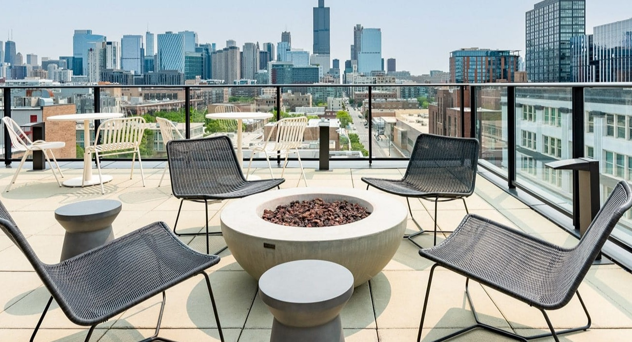 Stylish rooftop patio at The Jax in Chicago, featuring a modern fire pit, comfortable chairs, and panoramic city views