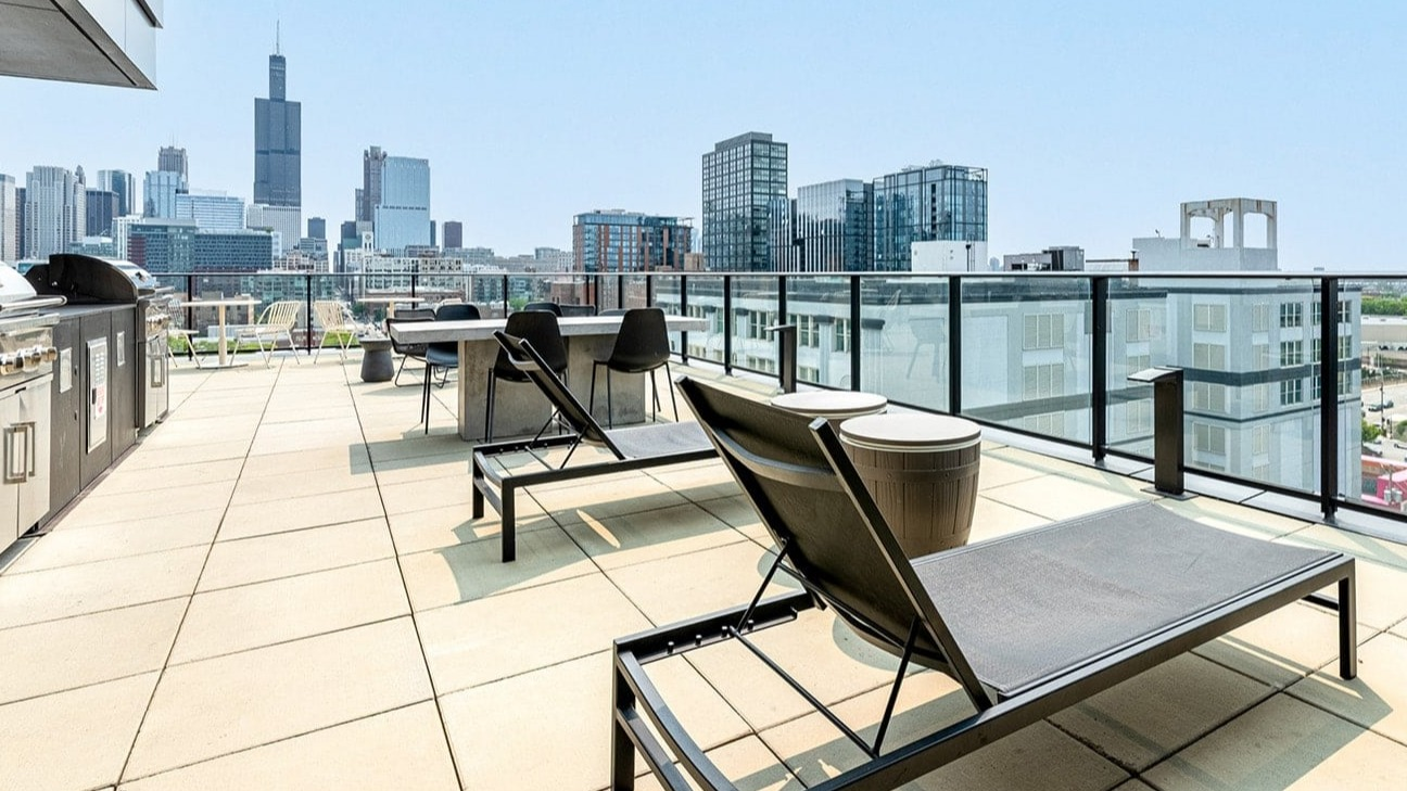 Expansive rooftop deck at The Jax in Chicago, featuring grilling stations, lounge chairs, and stunning city views