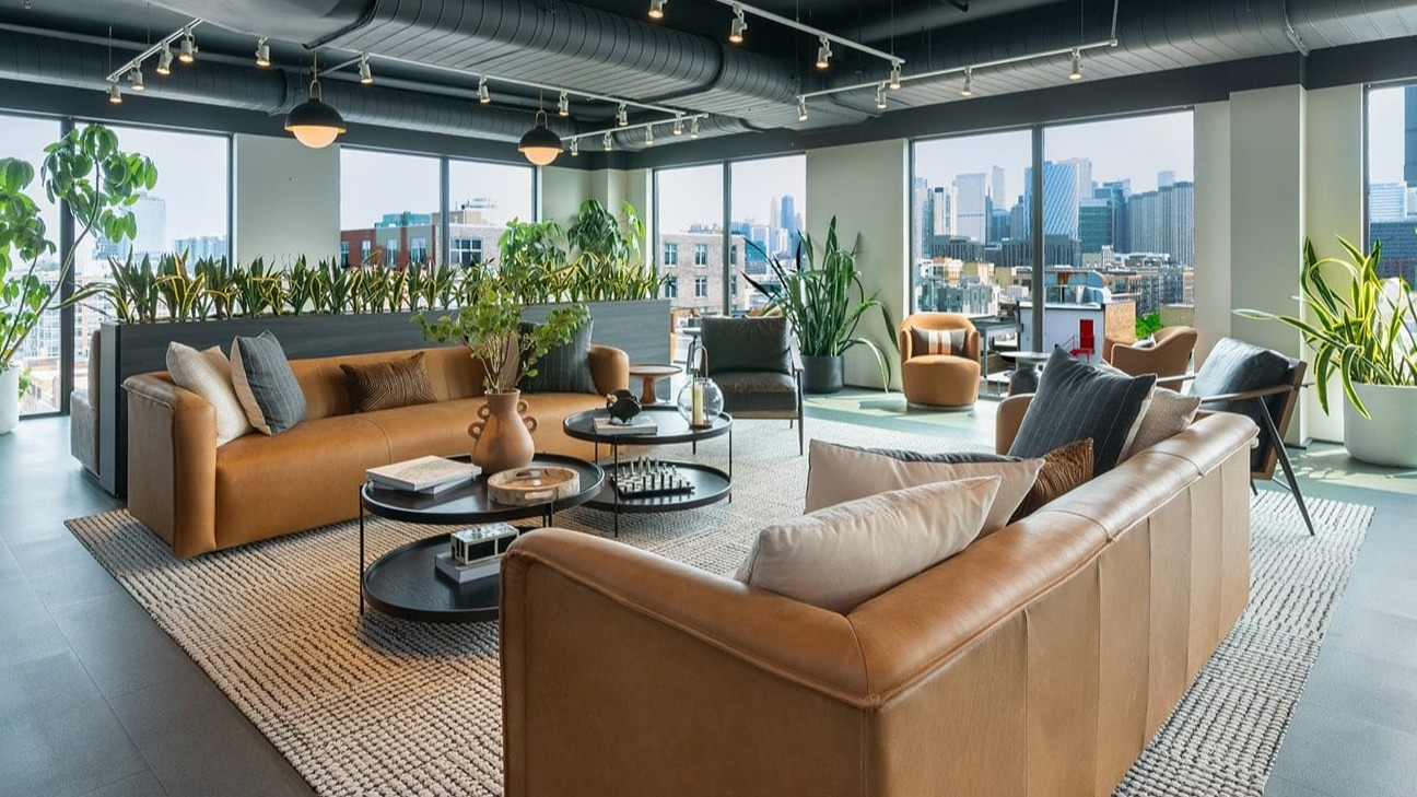 Spacious skyline lounge at The Jax in Chicago, featuring comfortable seating, lush greenery, and panoramic city views