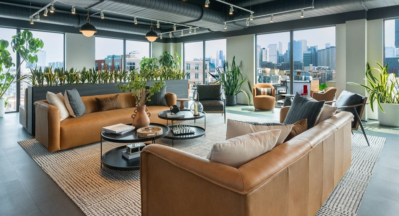 Spacious skyline lounge at The Jax in Chicago, featuring comfortable seating, lush greenery, and panoramic city views