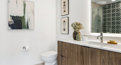 Modern bathroom at The Leo in Chicago, featuring a sleek wooden vanity, illuminated mirror, and a walk-in shower with patterned tiles