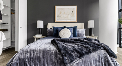 Cozy bedroom at The Leo in Chicago, featuring a comfortable bed with plush bedding, dark accent wall, and a walk-in closet