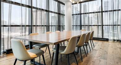 Elegant dining room at The Leo in Chicago, featuring a large wooden table, stylish chairs, and panoramic city views