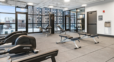 Spacious gym and fitness center at The Leo in Chicago, featuring cardio machines, weight equipment, and large windows