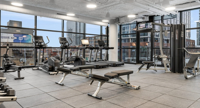 Comprehensive fitness center at The Leo in Chicago, featuring a wide range of weights, cardio machines, and city views