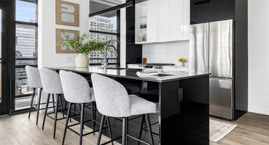 Modern apartment kitchen at The Leo in Chicago, featuring a black island with bar stools and stunning city views