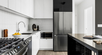 Sleek white kitchen at The Leo in Chicago, featuring stainless steel appliances, a gas range, and a modern black island