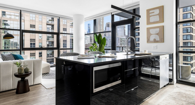 Bright open-concept living room and kitchen at The Leo in Chicago, featuring a modern sofa, stylish island, and expansive city views