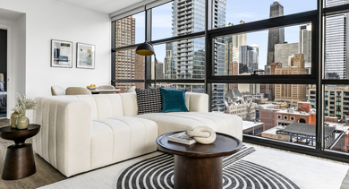 Bright living room at The Leo in Chicago, featuring a comfortable sofa, modern coffee table, and expansive city skyline views