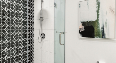 Modern apartment bathroom at The Leo in Chicago, featuring a stylish walk-in shower with geometric tile and modern art