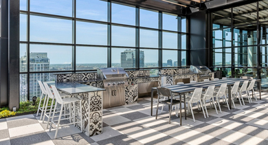 Modern rooftop dining area at The Leo in Chicago, featuring multiple grilling stations, large tables, and stunning city views
