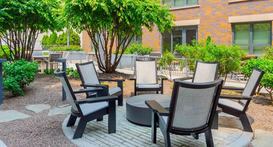A serene courtyard lounge area with comfortable chairs arranged around a central fire pit at The Madison at Racine apartments in Chicago
