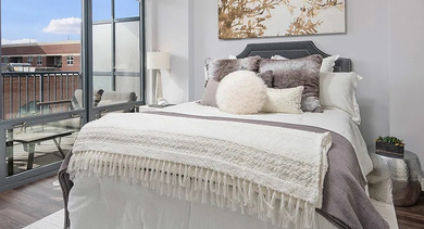A chic and cozy bedroom with a comfortable bed, stylish decor, and floor-to-ceiling windows leading to a private balcony at The Madison at Racine