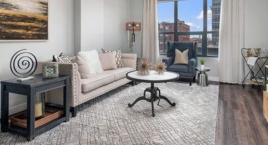 An elegantly decorated living room featuring a sofa, armchair, coffee table, and large window, perfect for comfortable living at The Madison at Racine