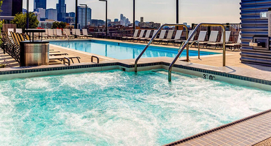A relaxing rooftop hot tub and swimming pool with ample seating, overlooking the vibrant Chicago skyline at The Madison at Racine