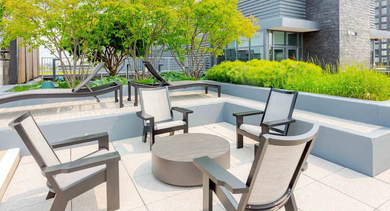 A tranquil section of the rooftop deck with comfortable chairs, a coffee table, and well-maintained greenery at The Madison at Racine in Chicago