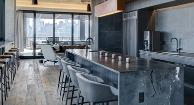 A state-of-the-art community kitchen and lounge area with a large island, bar seating, and stunning skyline views for residents at The Mason in Chicago