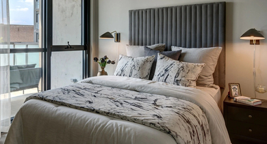 A contemporary and cozy bedroom with a comfortable bed, bedside lamps, and a large glass door leading to a private balcony at The Mason in Chicago