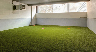 A clean and bright indoor dog run with artificial turf and plenty of space for pets to play at The Mason in Chicago