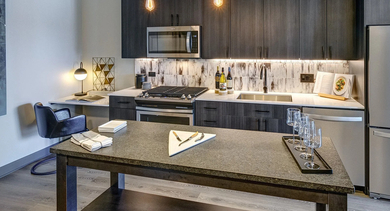 A modern kitchen with dark wood cabinets, stainless steel appliances, a large island, and a built-in desk area for convenience at The Mason in Chicago
