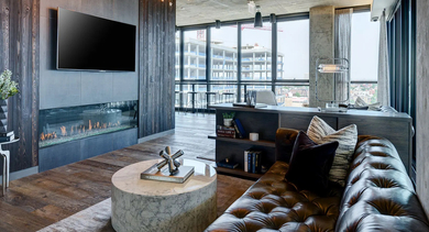 A luxurious resident lounge area with a fireplace, comfortable leather sofa, and expansive windows offering city views at The Mason in Chicago