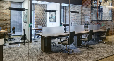 Modern, glass-enclosed private work nooks and shared co-working tables, providing versatile spaces for residents at The Mason in Chicago
