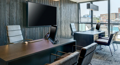 A professional resident co-working space featuring multiple desks, ergonomic chairs, and large windows overlooking the city at The Mason in Chicago