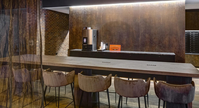 A stylish resident lounge with a coffee bar, long communal table, and modern pendant lighting at The Mason in Chicago