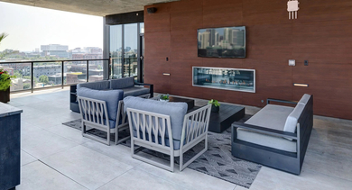 A sophisticated covered rooftop lounge area with a cozy fireplace, wall-mounted TV, and comfortable outdoor seating at The Mason in Chicago