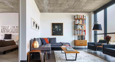 A spacious and elegantly furnished living room with a comfortable sofa, armchair, and a prominent bookshelf at The Mason apartments in Chicago