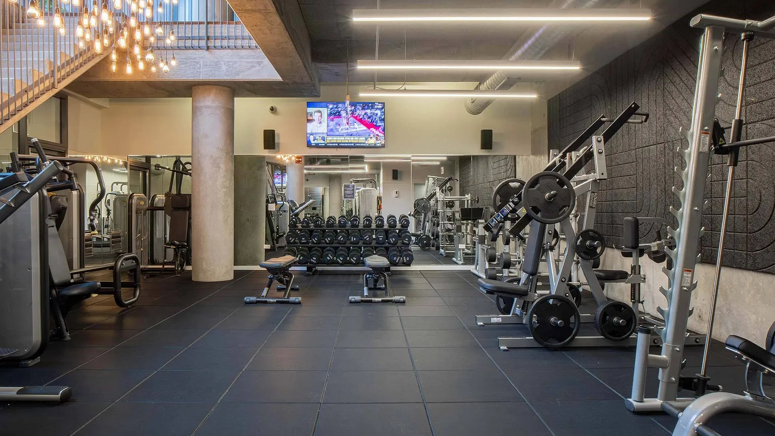 A well-equipped fitness center with various weight machines, free weights, and modern lighting, accessible to residents at The Parker Fulton Market in Chicago