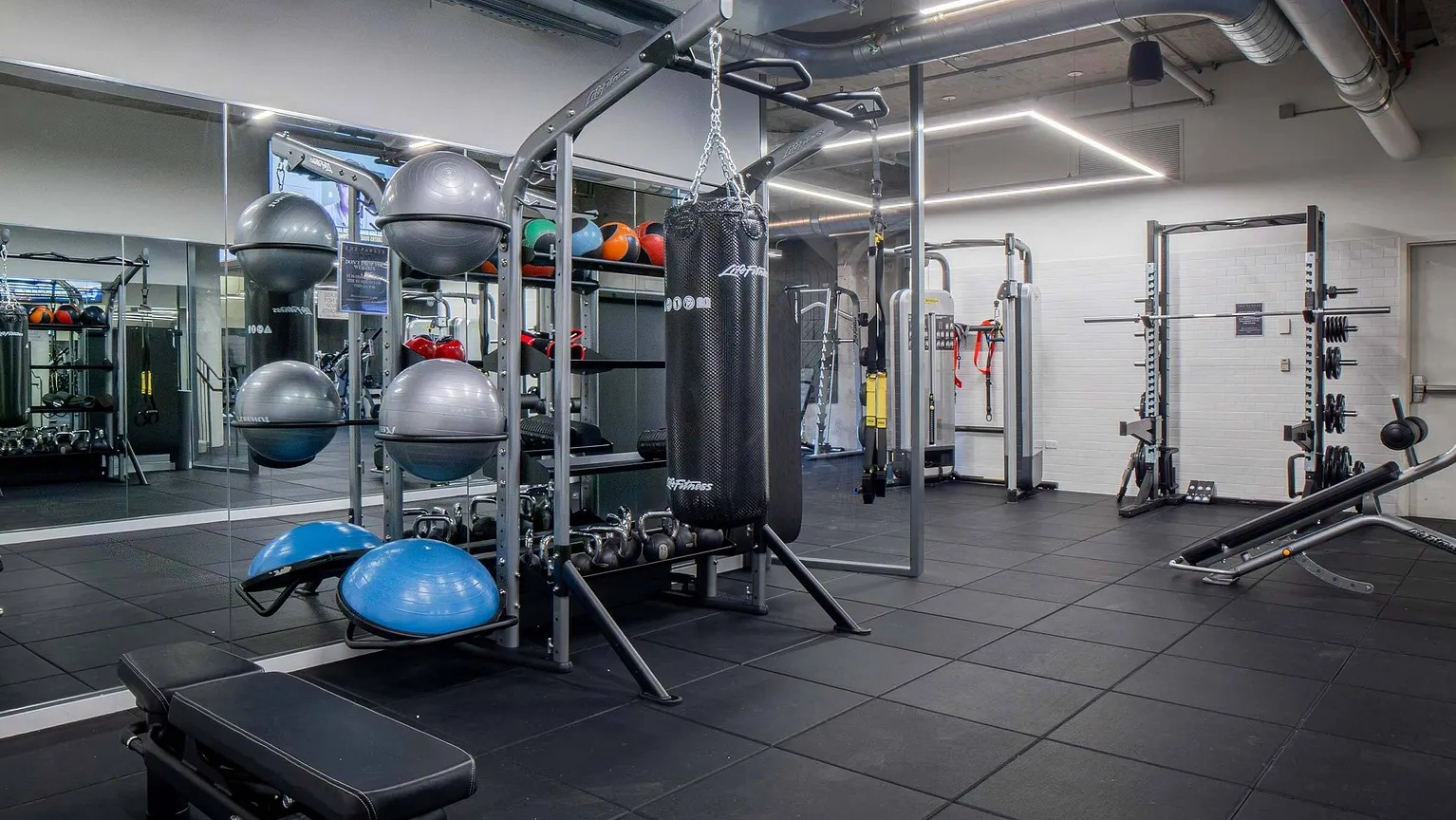 A dynamic gym space featuring a punching bag, functional training equipment, and free weights, perfect for diverse workouts at The Parker Fulton Market in Chicago