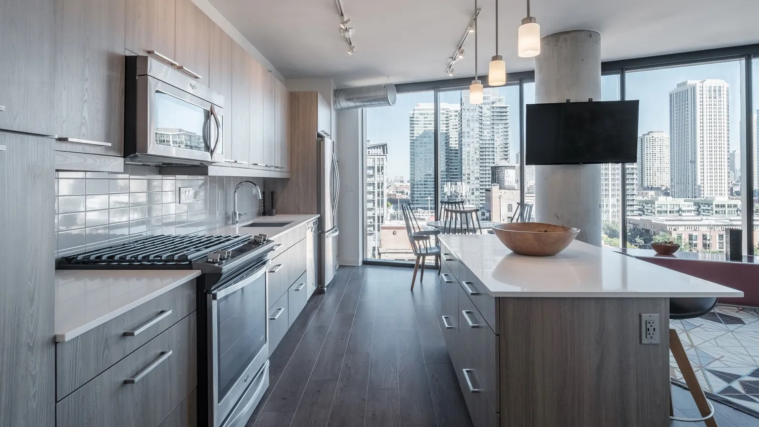 A sleek, modern kitchen with light wood cabinetry, stainless steel appliances, and a kitchen island with stunning city views at The Parker Fulton Market in Chicago