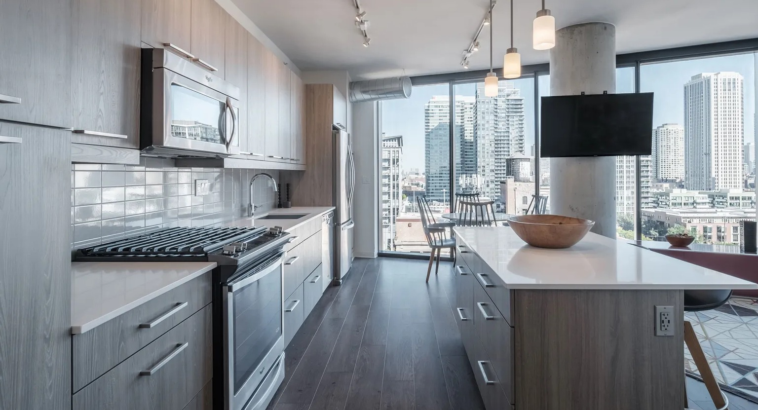 A sleek, modern kitchen with light wood cabinetry, stainless steel appliances, and a kitchen island with stunning city views at The Parker Fulton Market in Chicago