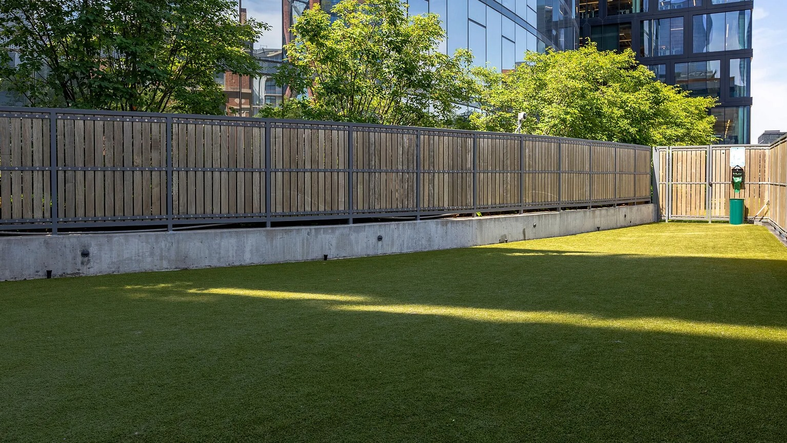 A spacious and well-maintained outdoor dog park with artificial turf and a wooden fence, ideal for pets at The Parker Fulton Market in Chicago