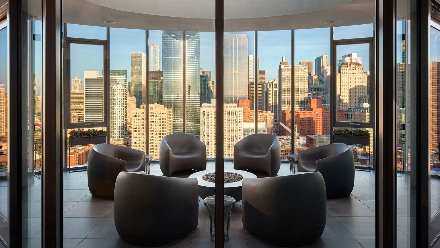 An elegant rooftop sky lounge with modern seating arranged around a fire pit, offering spectacular panoramic views of the Chicago skyline at The Parker Fulton Market
