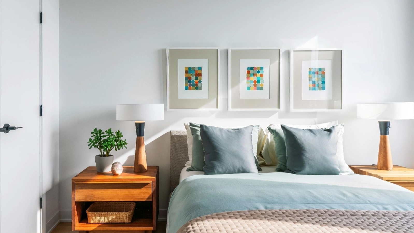 A comfortable and modern bedroom with a queen-sized bed, stylish bedside tables, lamps, and colorful framed artwork at The Reed in Chicago