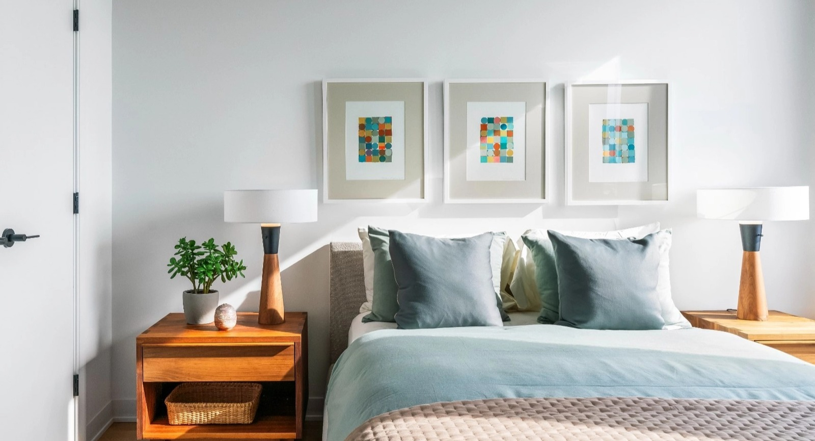 A comfortable and modern bedroom with a queen-sized bed, stylish bedside tables, lamps, and colorful framed artwork at The Reed in Chicago