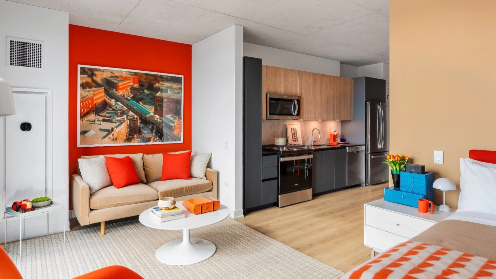 A vibrant, open-concept studio apartment with a modern kitchen, living area, and bedroom, featuring colorful accents at The Reed in Chicago