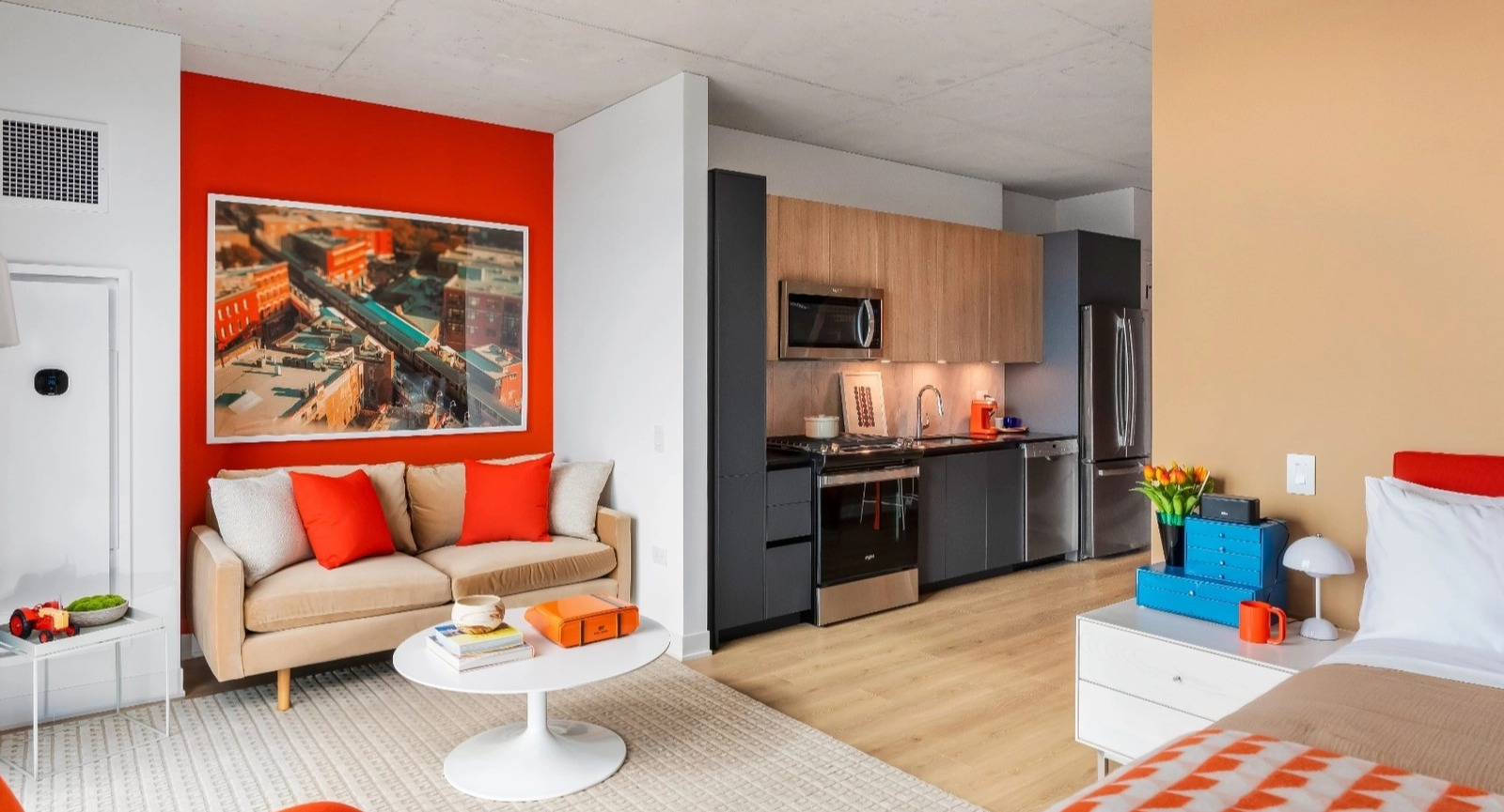 A vibrant, open-concept studio apartment with a modern kitchen, living area, and bedroom, featuring colorful accents at The Reed in Chicago
