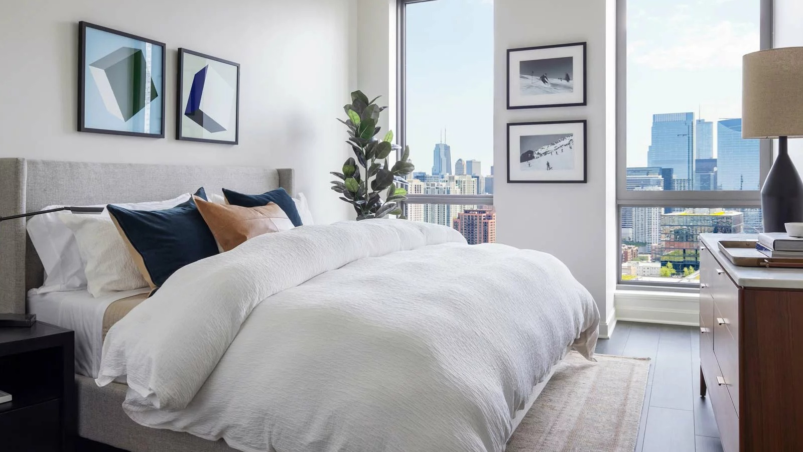 Stylish bedroom at The Row Fulton Market in Chicago, featuring a comfortable bed, modern decor, and expansive city views from large windows