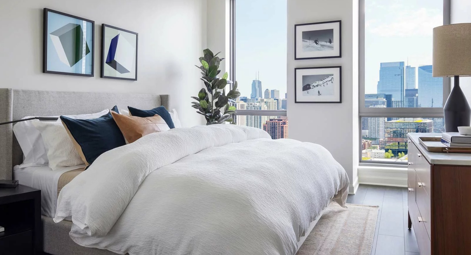 Stylish bedroom at The Row Fulton Market in Chicago, featuring a comfortable bed, modern decor, and expansive city views from large windows