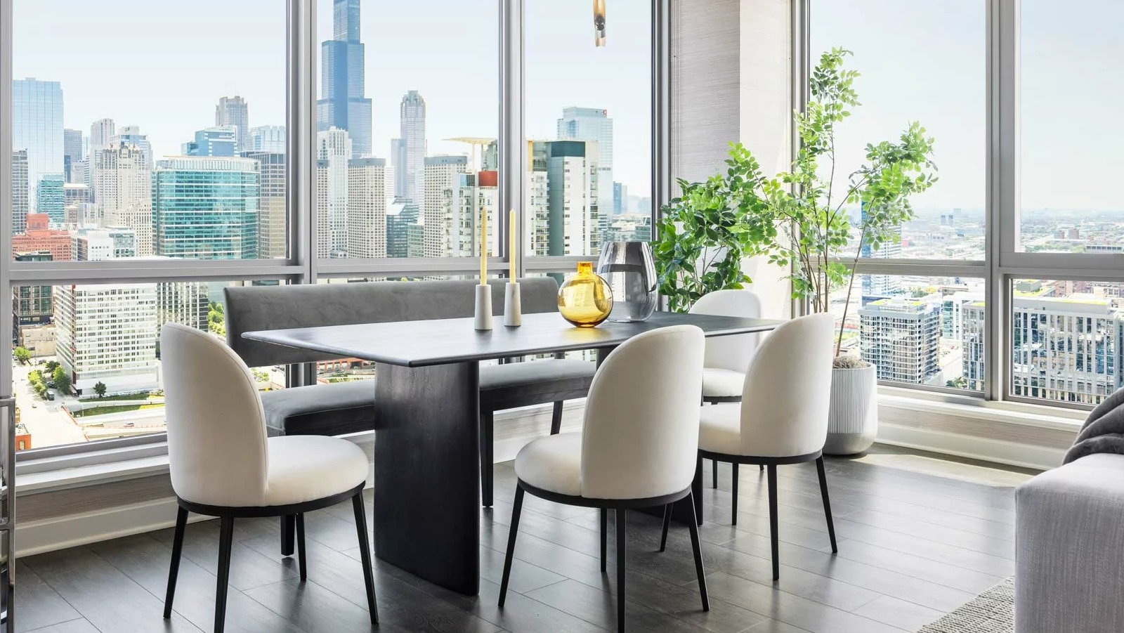 Elegant dining area at The Row Fulton Market in Chicago, featuring a long table, bench seating, and dramatic city skyline views