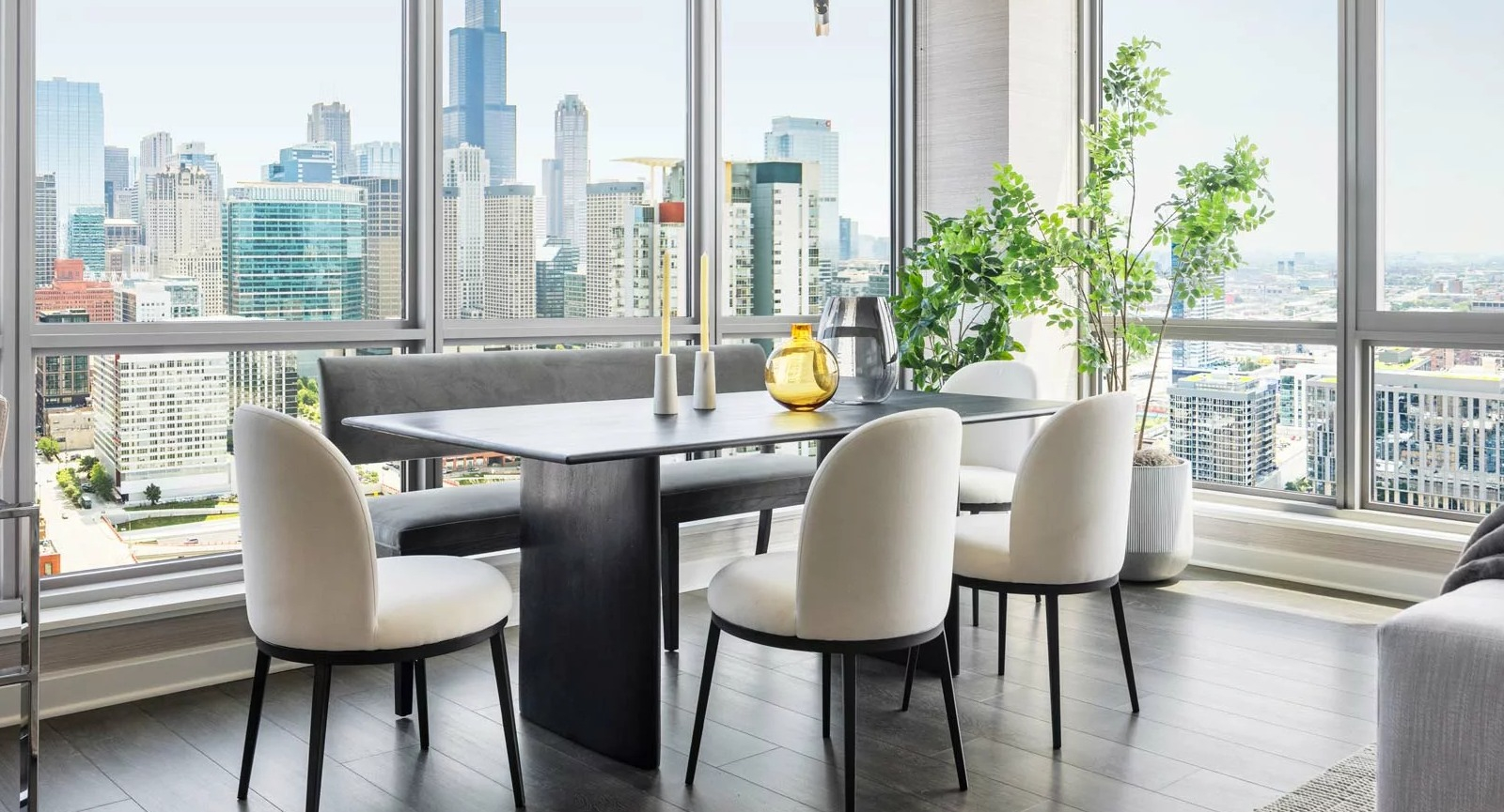 Elegant dining area at The Row Fulton Market in Chicago, featuring a long table, bench seating, and dramatic city skyline views