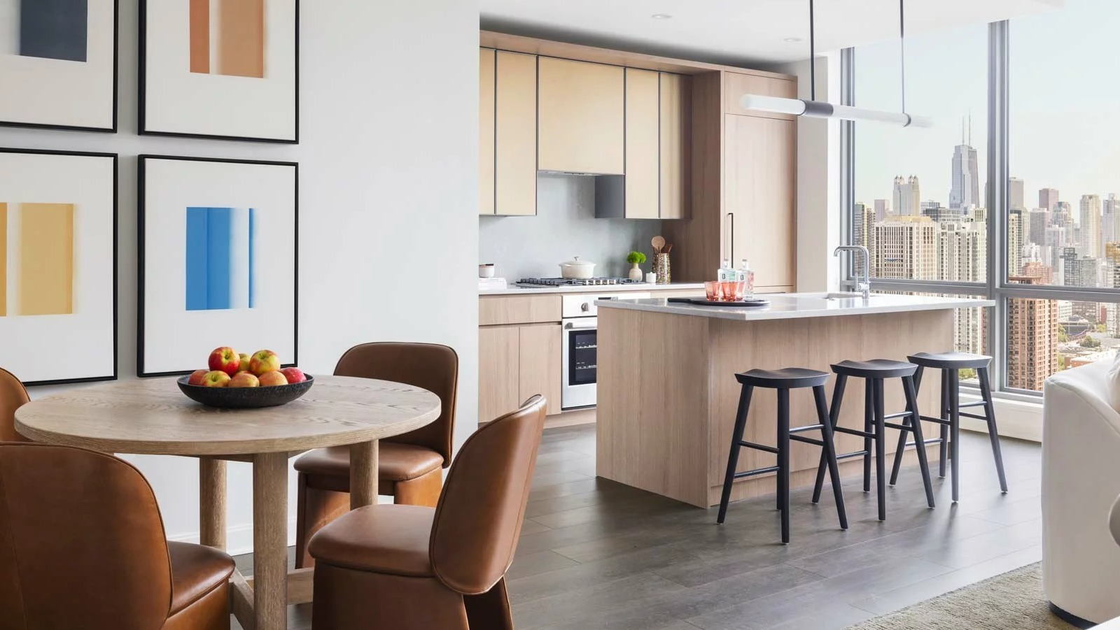 Contemporary kitchen and dining area at The Row Fulton Market in Chicago, with light wood cabinetry, a round dining table, and city views