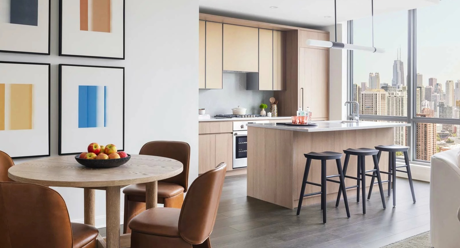 Contemporary kitchen and dining area at The Row Fulton Market in Chicago, with light wood cabinetry, a round dining table, and city views